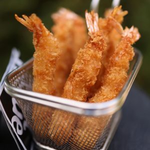 Close-up of delicious golden fried shrimps served in a metal basket.