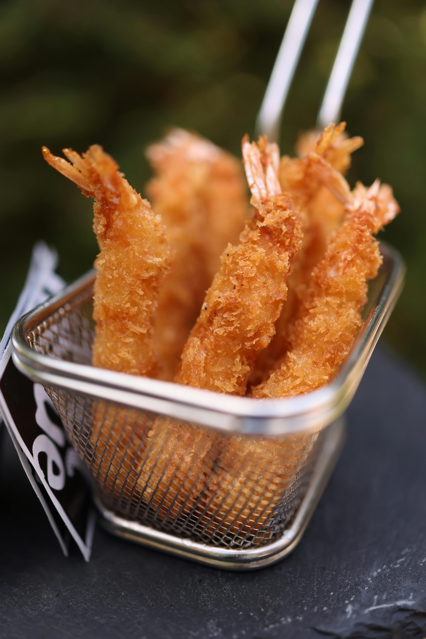 Close-up of delicious golden fried shrimps served in a metal basket.