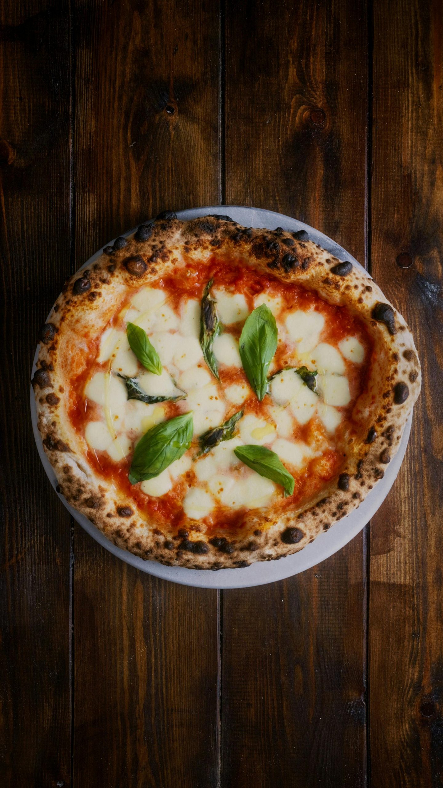 Savory Margherita pizza with fresh basil and mozzarella on a wooden table.