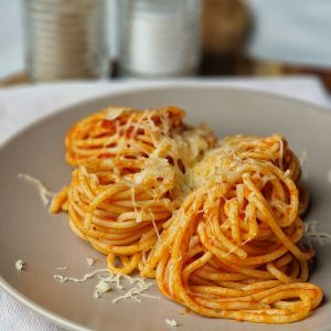 Plate of spaghetti topped with tomato sauce and grated cheese, perfect for Italian cuisine lovers.